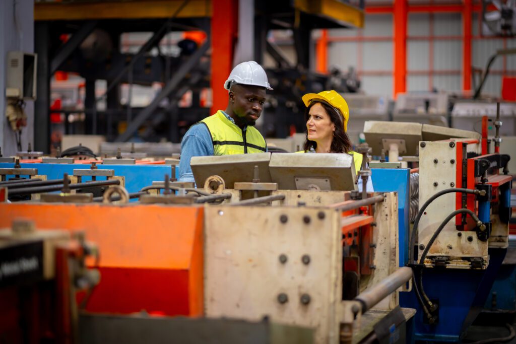 Team of young male and female engineers in a metal sheet factory